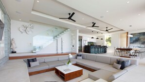 A spacious living area with a large sectional sofa, a wooden coffee table, and a staircase leading to an upper level. - Villa Zest at Lime Samui (Koh Samui)