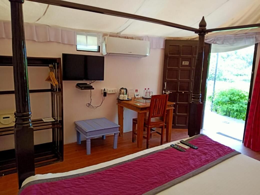 Ein Zimmer mit einem Bett, einem Schreibtisch, einem Sessel, einem Fernseher und einer Klimaanlage.