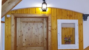 Eine Holztür mit kleinem Fenster darüber, eine Lampe über der Tür und eine Holzwand mit gelbem Akzent.