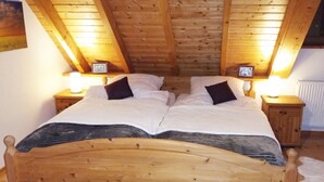 Ein hölzernes Bett in einem Raum mit schrägen Decken und Holzwänden.