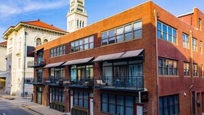 A two-story building with large windows and a balcony. - Large Condo In Prime Downtown Location w/ Balcony by Lucky Savannah (Savannah)
