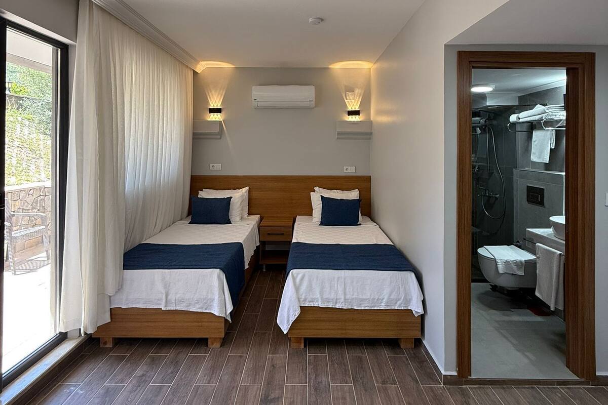 Een hotelkamer met twee bedden, een badkamer en uitzicht op de omgeving.