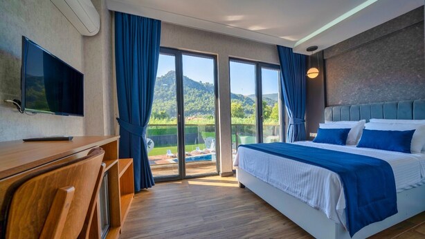 Une chambre d’hôtel équipée d’un lit, d’un bureau, d’une télévision et offrant une vue sur une piscine et des montagnes.