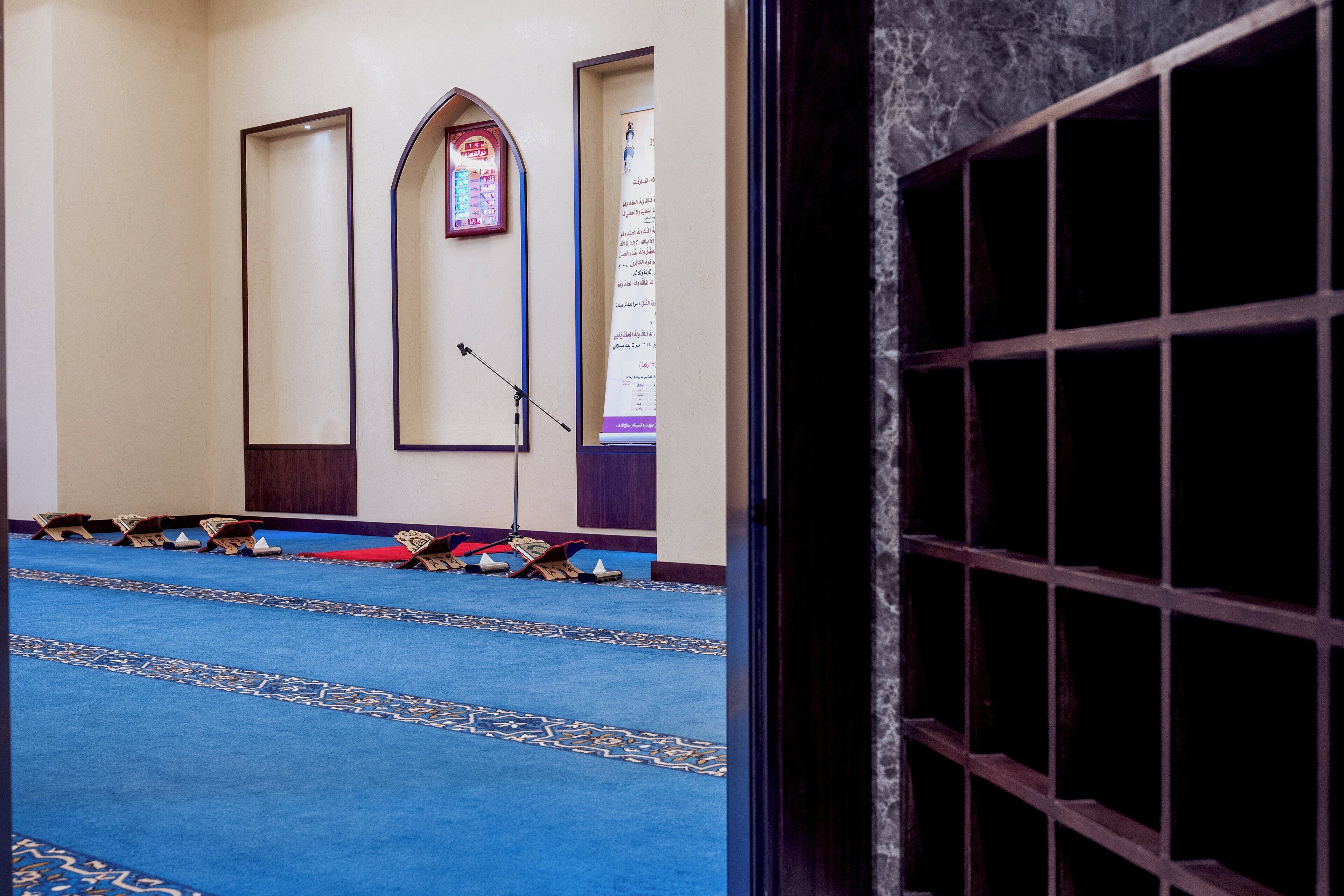 Una habitación con alfombra azul, un soporte para micrófono y una puerta con diseño de cuadrícula.