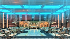 A banquet hall with a central stage, rows of tables, and chairs. - Grand Millennium Tabuk (Tabuk)