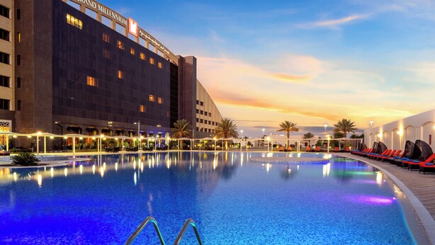 A swimming pool with lounge chairs and a hotel building in the background. - Grand Millennium Tabuk (Tabuk)