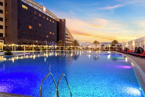 Una piscina con sillas de descanso y un hotel al fondo.