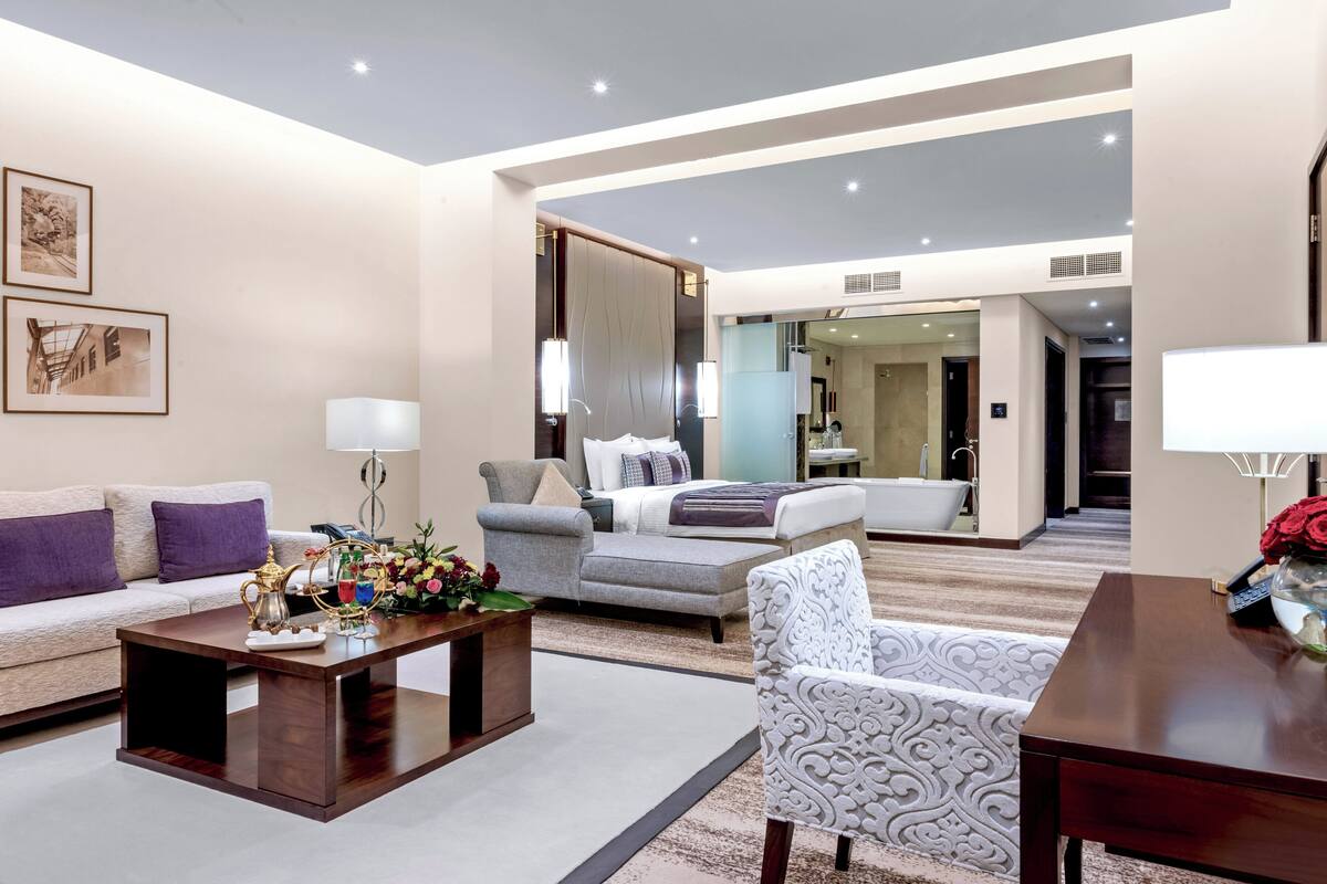 A modern hotel room with a living area, a sofa, a coffee table, and a decorative vase.