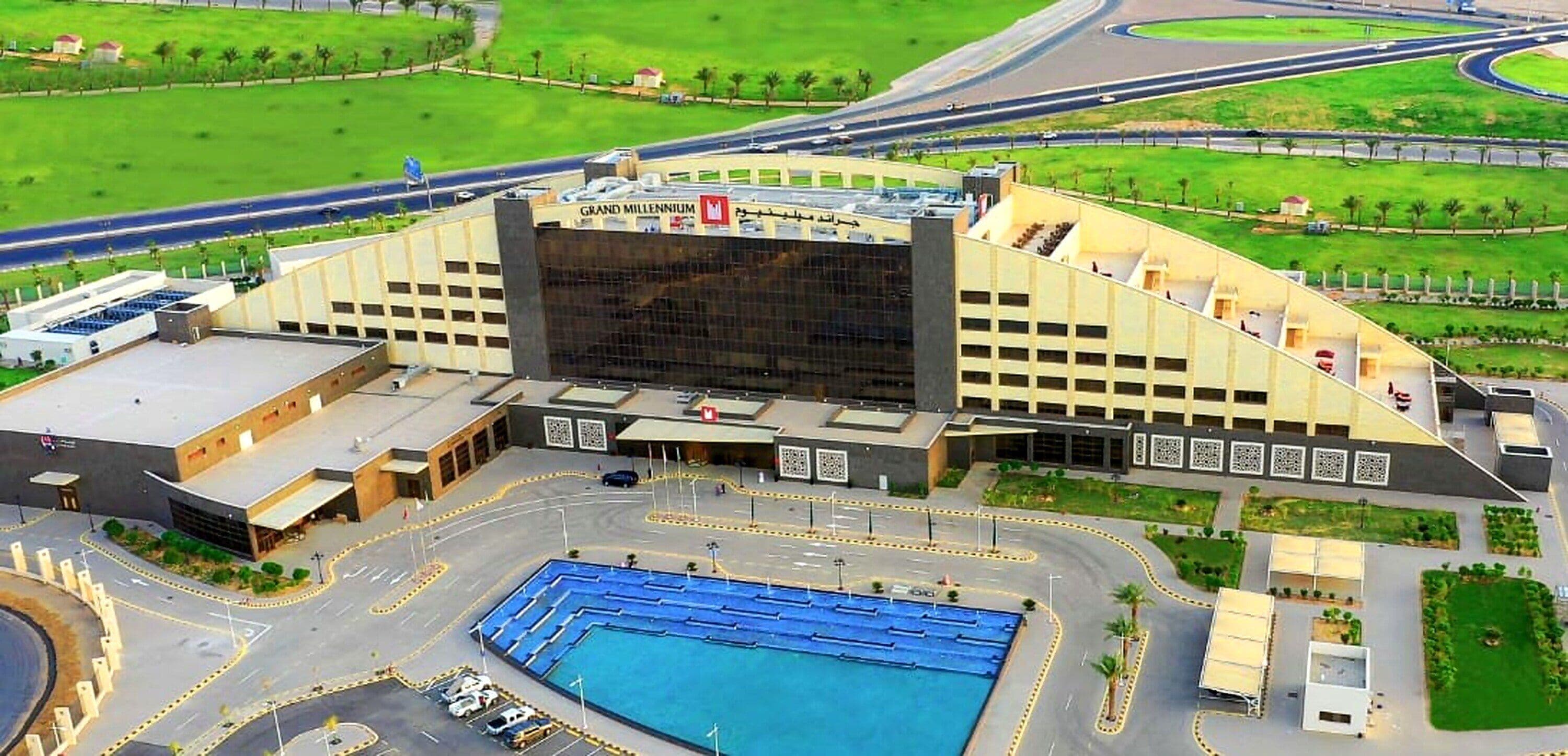 A large building with a prominent entrance and a swimming pool in front.