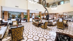 A spacious lobby with a geometric patterned floor, multiple seating areas, and a modern chandelier. - Grand Millennium Tabuk (Tabuk)