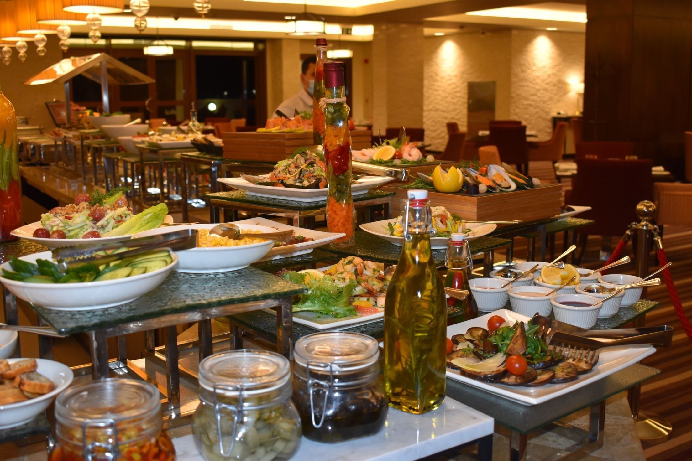 A buffet setup with various dishes, including salads, seafood, and bread, arranged on tables.