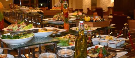 A buffet setup with various dishes, including salads, seafood, and bread, arranged on tables.