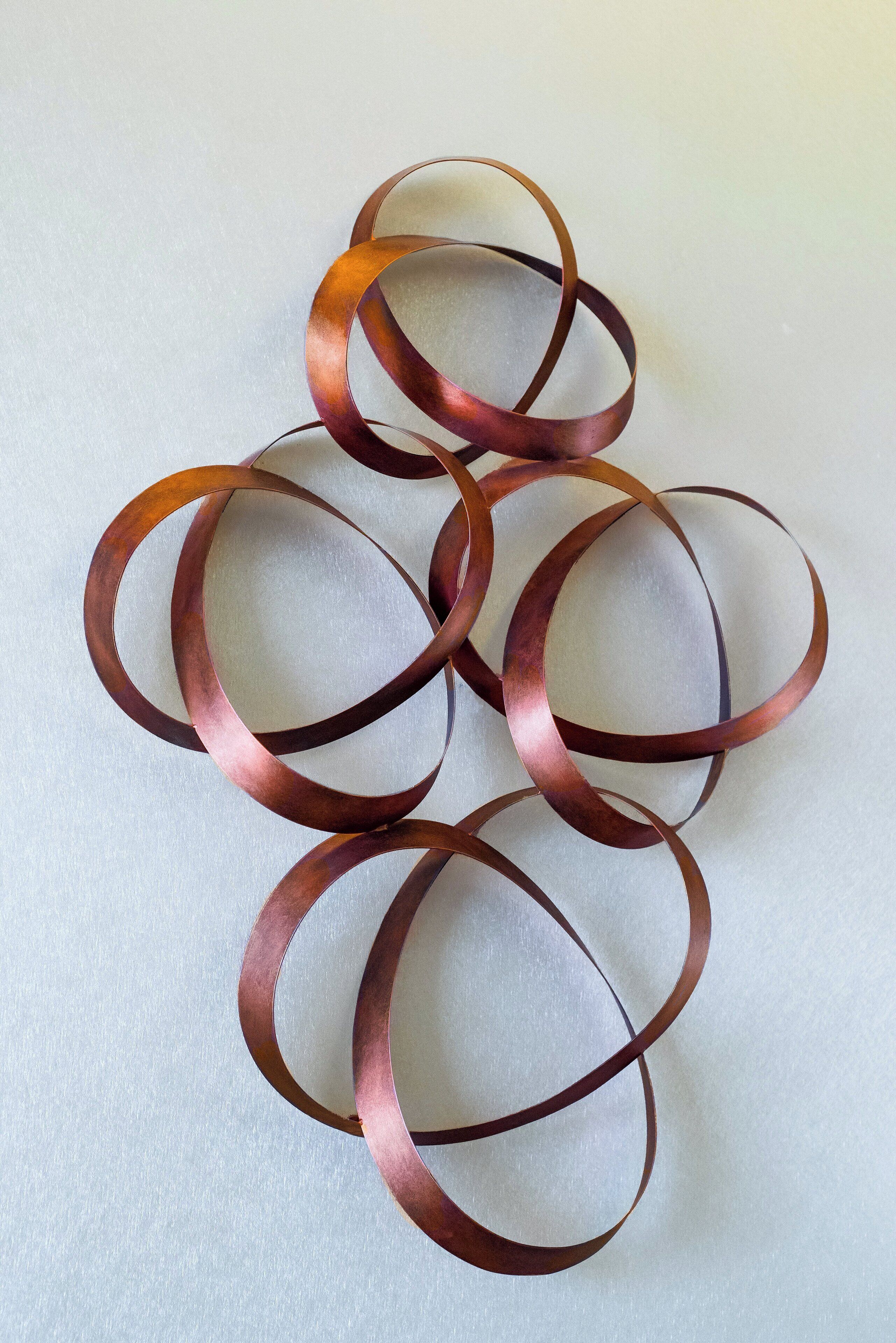 A close-up of interwoven copper rings on a textured surface.