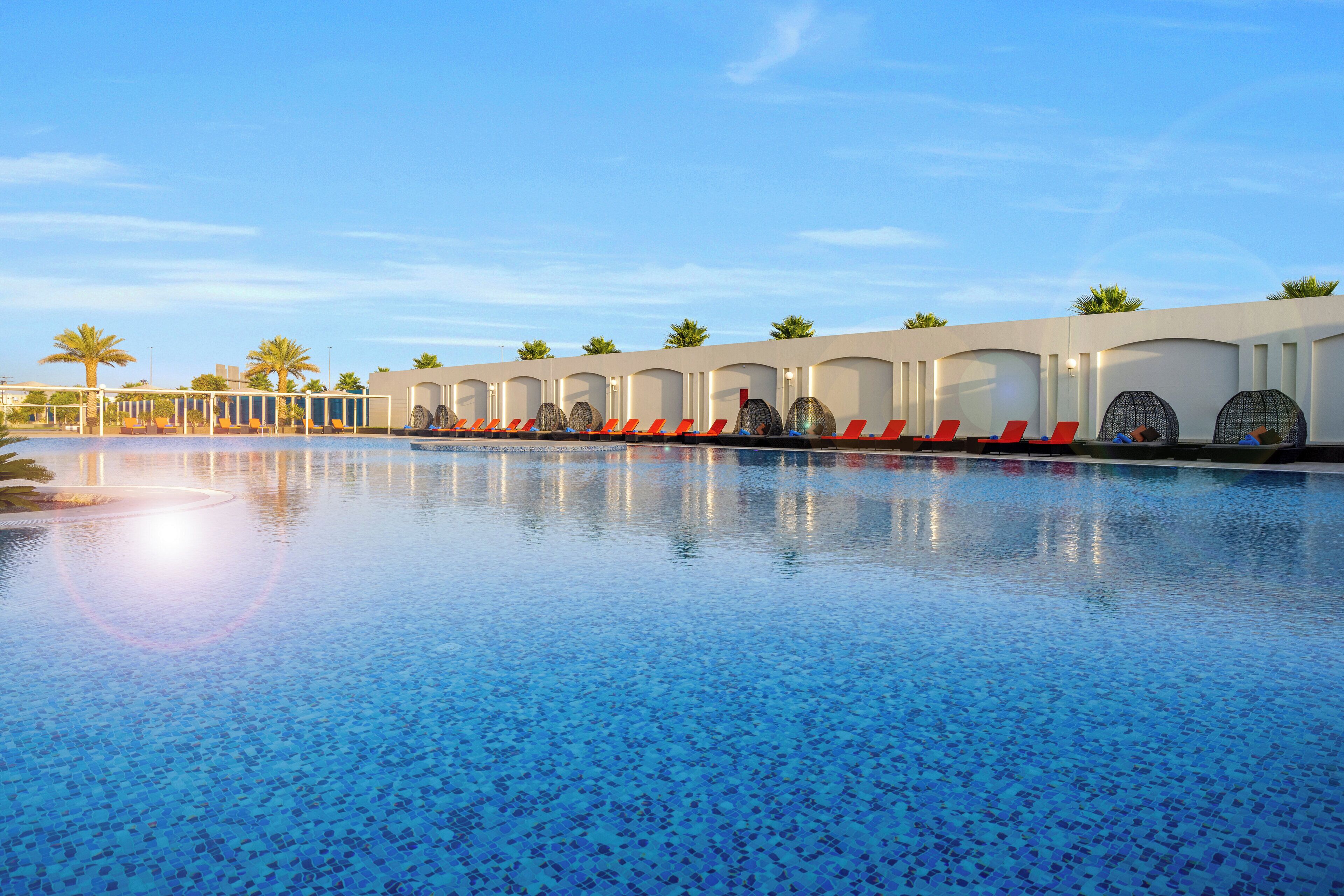 Una piscina con sillones de descanso y palmeras.