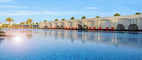 Una piscina con sillones de descanso y palmeras.