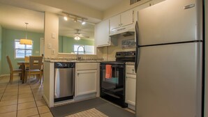 Una cocina con refrigerador, horno, lavavajillas y un comedor con sillas y una mesa.