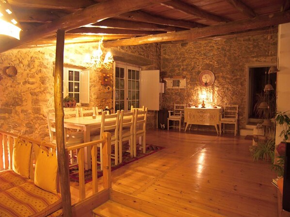A rustic dining area with a stone wall, wooden furniture, and a chandelier.
