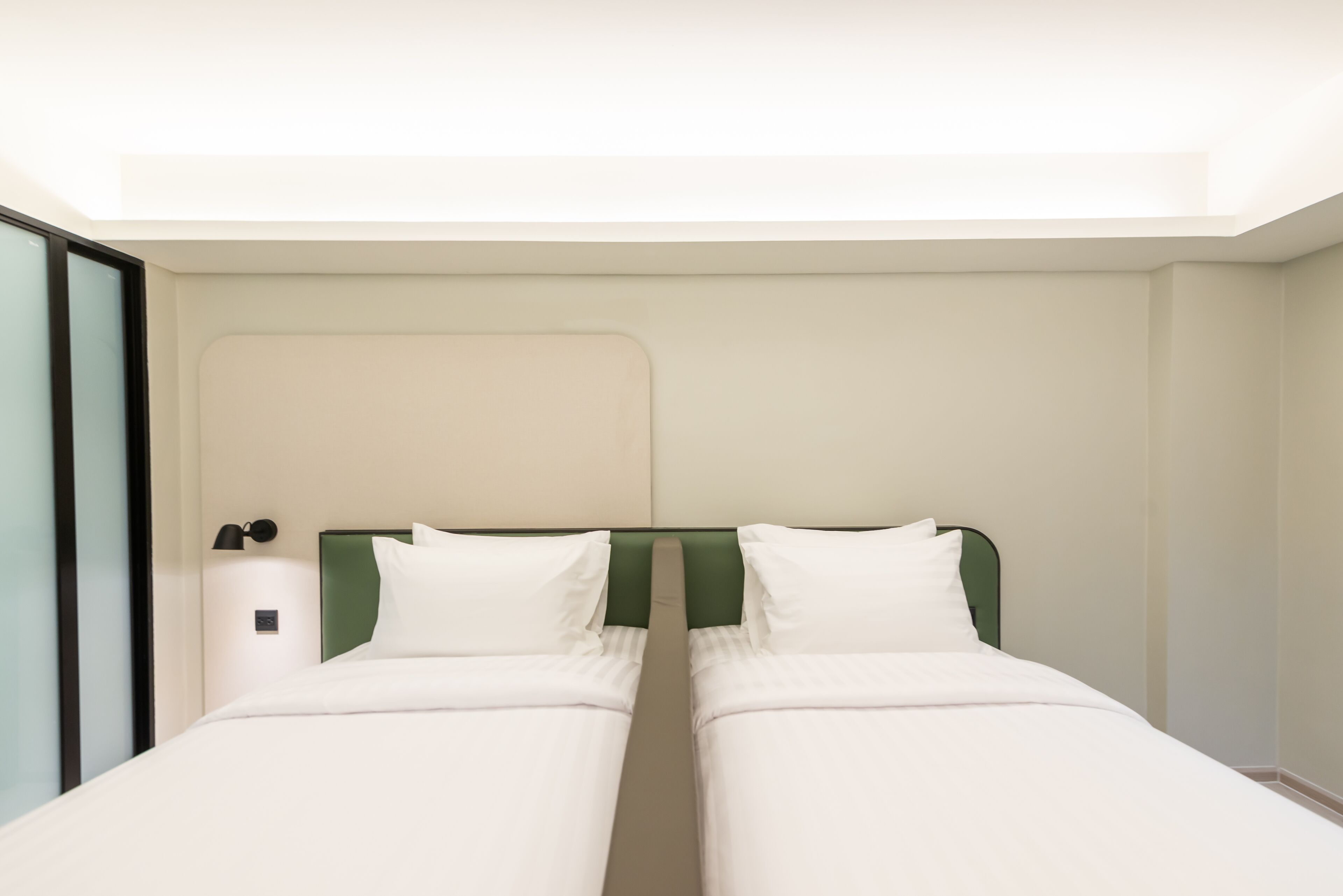 Uma cama de casal com cabeceira verde num quarto de hotel.