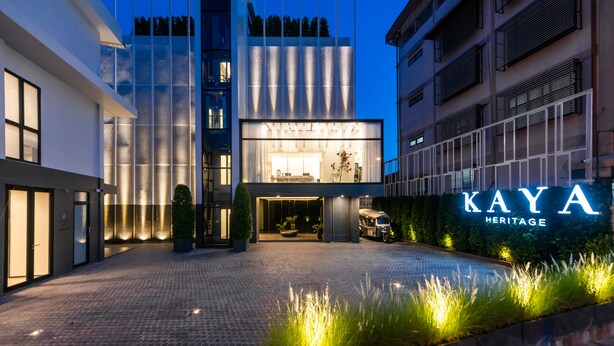 Ein moderner Hotelaufgang mit einer gut beleuchteten Fassade, einem gut sichtbaren Schild mit der Aufschrift "KAYA HERITAGE" und einer gepflasterten Auffahrt zum Eingang.