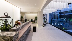 Ein moderner Empfangsbereich mit einer Marmor-Theke, einem schwarzen Hocker und Blick auf die Stadt durch ein großes Fenster.