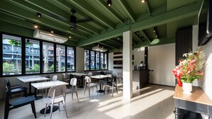 Ein modernes Café mit Tischen, Stühlen, großen Fenstern und einer dekorativen Blumenkomposition.