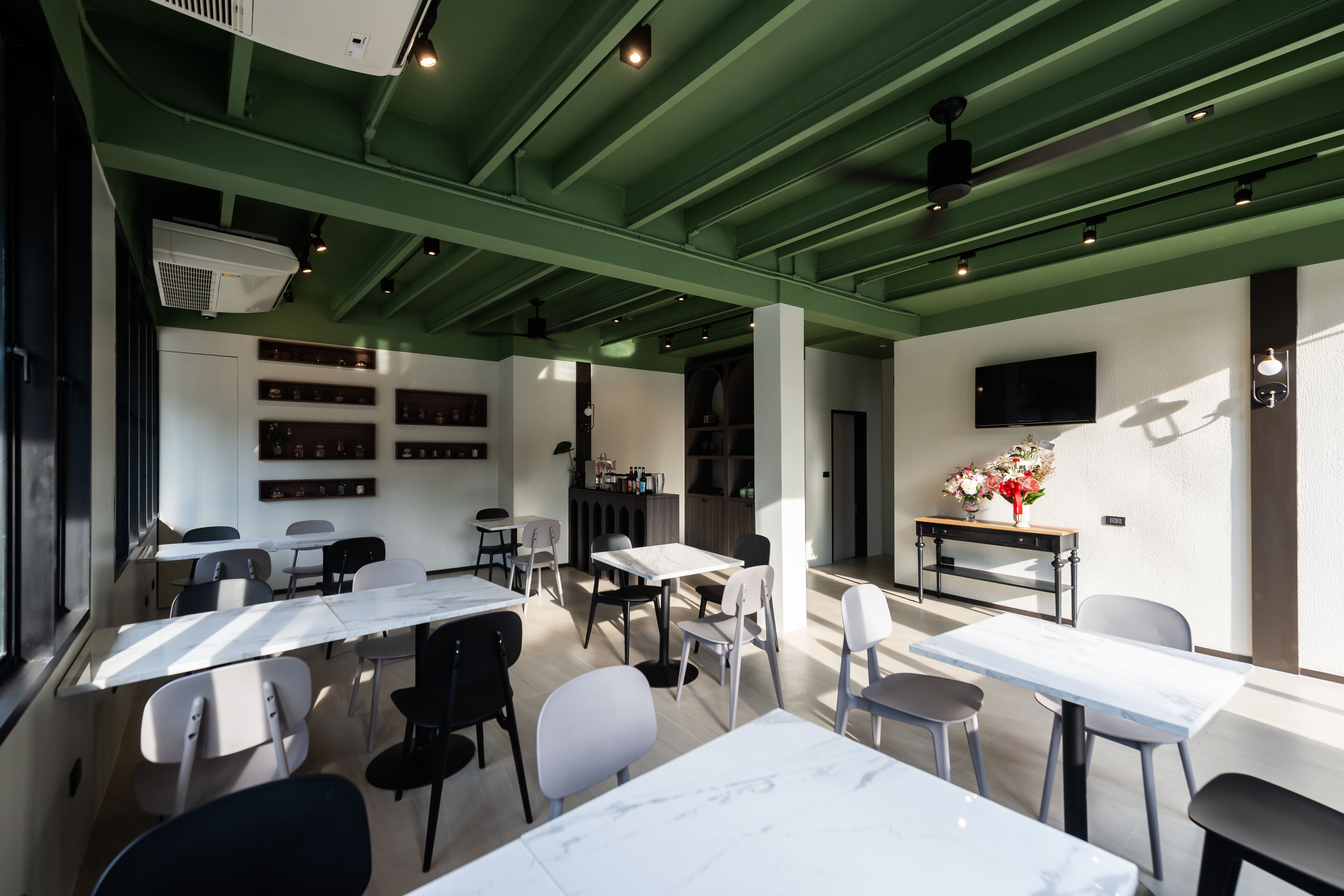 A modern dining area with tables and chairs, a television, and a flower arrangement.