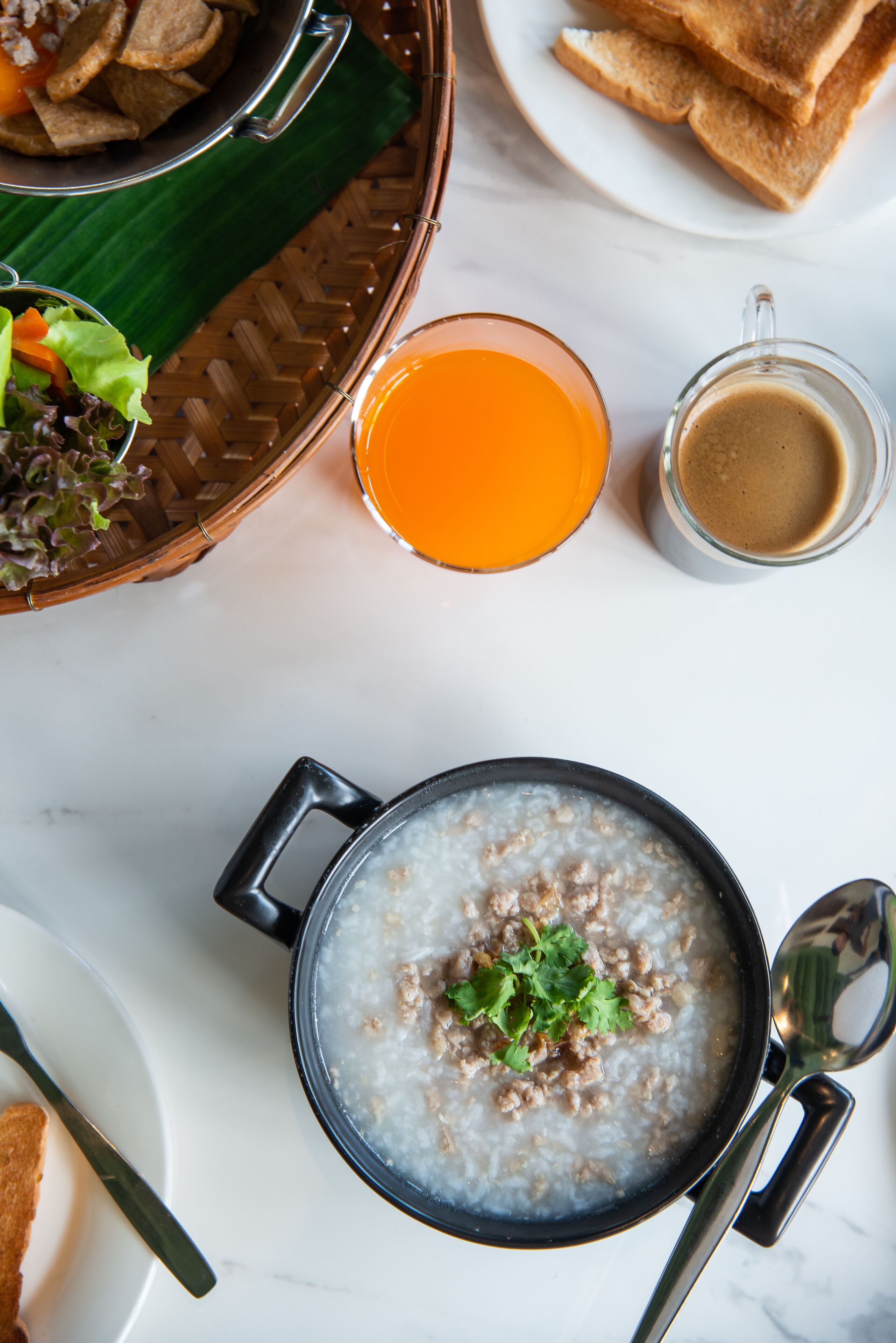 Une table mise pour le petit-déjeuner avec un bol de porridge, des toasts, un verre de jus d’orange et une tasse de café.
