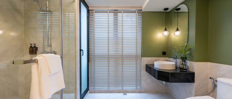 Un baño moderno con cabina de ducha de vidrio, inodoro y lavabo con tocador.