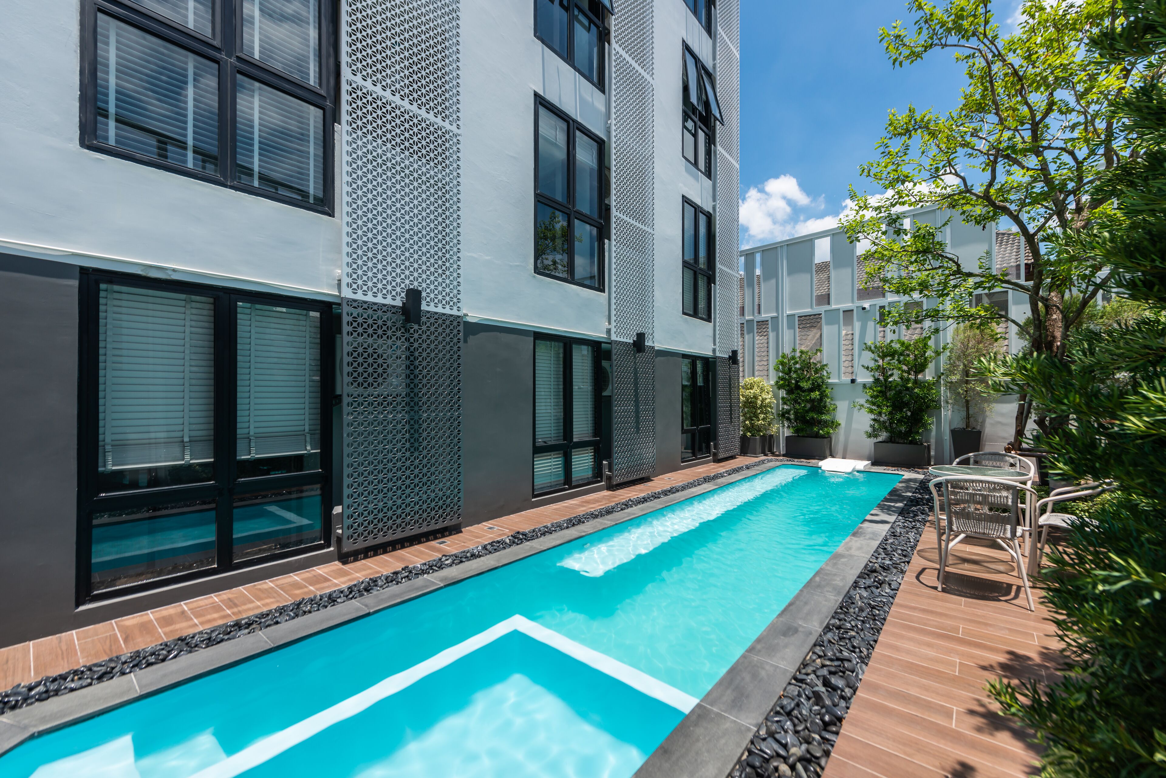 A modern building with a swimming pool, large windows, and outdoor seating.