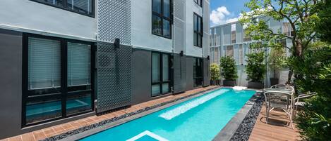 A modern building with a swimming pool, large windows, and outdoor seating.