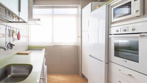 Una cocina con pileta, armarios, ventana y microondas.