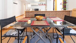 Un comedor moderno con una mesa de vidrio, sillas negras y caminos de mesa rojos.