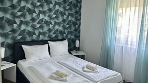 A modern hotel room with a geometric-patterned headboard, a large bed with white linens, two bedside tables, and a window with sheer curtains. - Residence Beni 6 with large heated pool (Medulin, Pula)