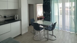Une cuisine moderne avec des meubles blancs, une table à manger et quatre chaises, ainsi qu’un canapé.