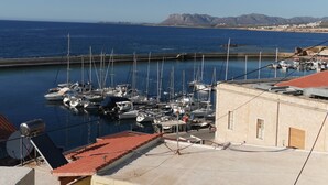 Un port de plaisance avec des bateaux amarrés, un ciel dégagé et des montagnes en arrière-plan.