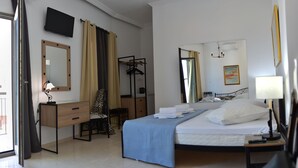 Une chambre d’hôtel comprenant un lit, un bureau, une chaise, une armoire, un miroir, une télévision et une fenêtre.