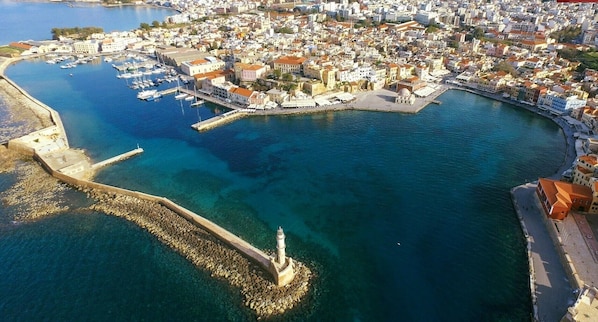 Vue aérienne d’une ville côtière avec un port de plaisance, un phare et un mélange de bâtiments résidentiels et commerciaux.