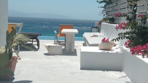 Eine Terrasse mit Meerblick, ausgestattet mit Sitzgelegenheiten und einer Kakteepflanze.