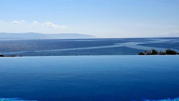 Ein klarer Blick auf einen Pool mit Meerblick und entfernten Bergen.
