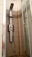 Uma casa de banho moderna com cabine de duche em vidro, chuveiro fixo na parede e chuveiro de mão.