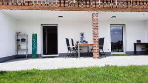 Una zona relax esterna moderna con tavolo e sedie, un cartello di benvenuto e un pilastro in mattoni.