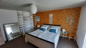 Una camera da letto con un letto, un armadio, uno specchio, un tavolino e una lampada a sospensione.