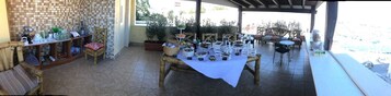 Un espacio al aire libre con patio, mesa de comedor lista para una comida, sillas y una mesa de buffet con diversos alimentos.
