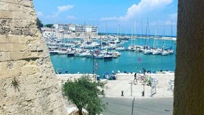 A marina with numerous boats docked, a clear blue sky, and a stone wall on the left. - B&B Al Porto Novo (Bisceglie)