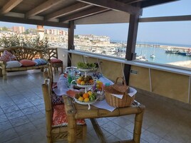Un balcón con una mesa dispuesta para una comida, con frutas y una cesta.