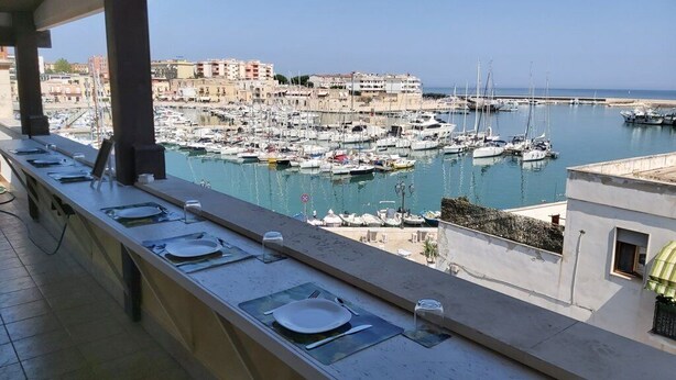 A balcony with a view of a marina and buildings in the background. - B&B Al Porto Novo (Bisceglie)