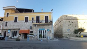 A building with a yellow facade, a stone base, and a sign reading "Cafeteria". - B&B Al Porto Novo (Bisceglie)