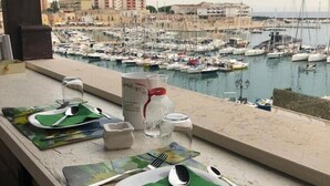 A table set with green placemats, white plates, and silverware overlooking a marina with numerous boats. - B&B Al Porto Novo (Bisceglie)