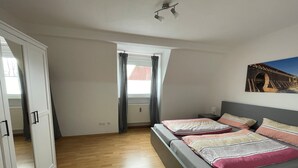 Un dormitorio con cama, armario, radiador y ventana con cortinas.