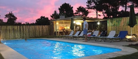 Una piscina al aire libre, sombrillas, tumbonas